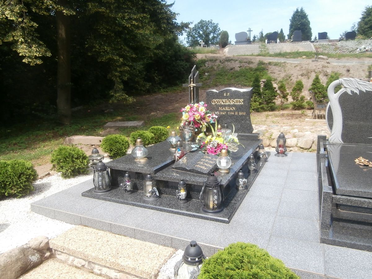grób z wieloma zniczami i kwiatami
