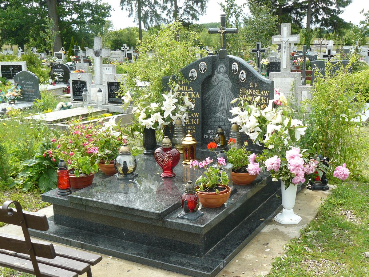 duży podwójny pomnik grobowiec, dużo zieleni, kwiatów i zniczy